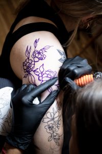 Tatuowanie delikatnego motywu kwiatowego, przy którym można się zastanawiać, czy tatuaż boli.